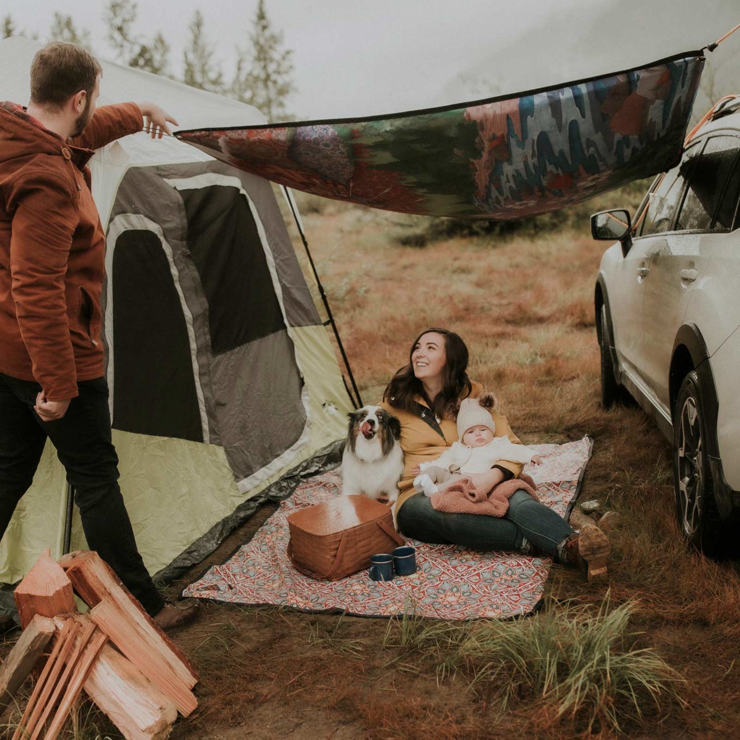 Young couple with newborn and dog camping with Tarpestry picnic blanket