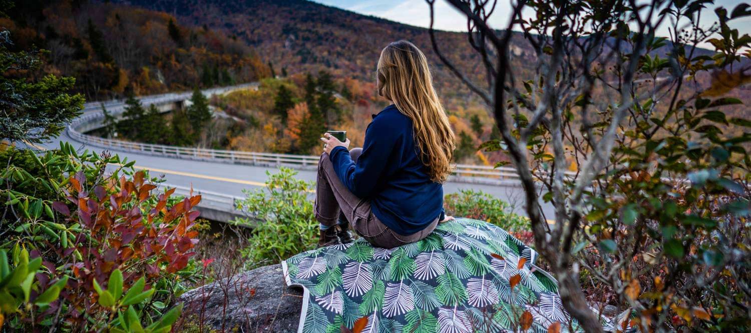 Woman sitting on Frond Tarpestry on a rock overlooking Blue Ridge Parkway.